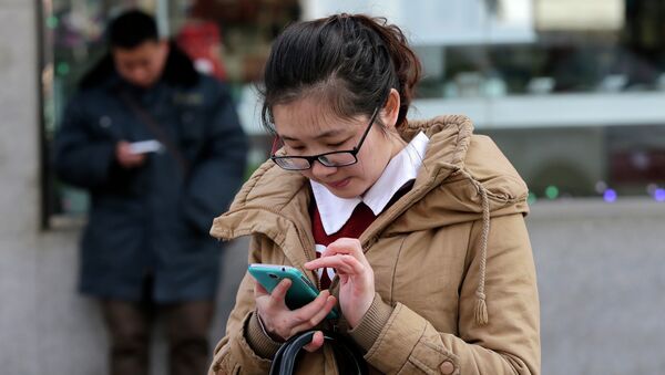 Los chinos comprueban sus teléfonos en una calle de Beijing - Sputnik Mundo