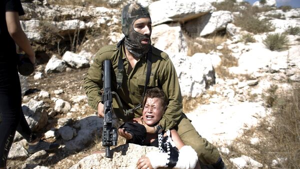 Un soldado israelí detiene a un niño palestino durante una protesta en la aldea cisjordana de Nabi Saleh - Sputnik Mundo