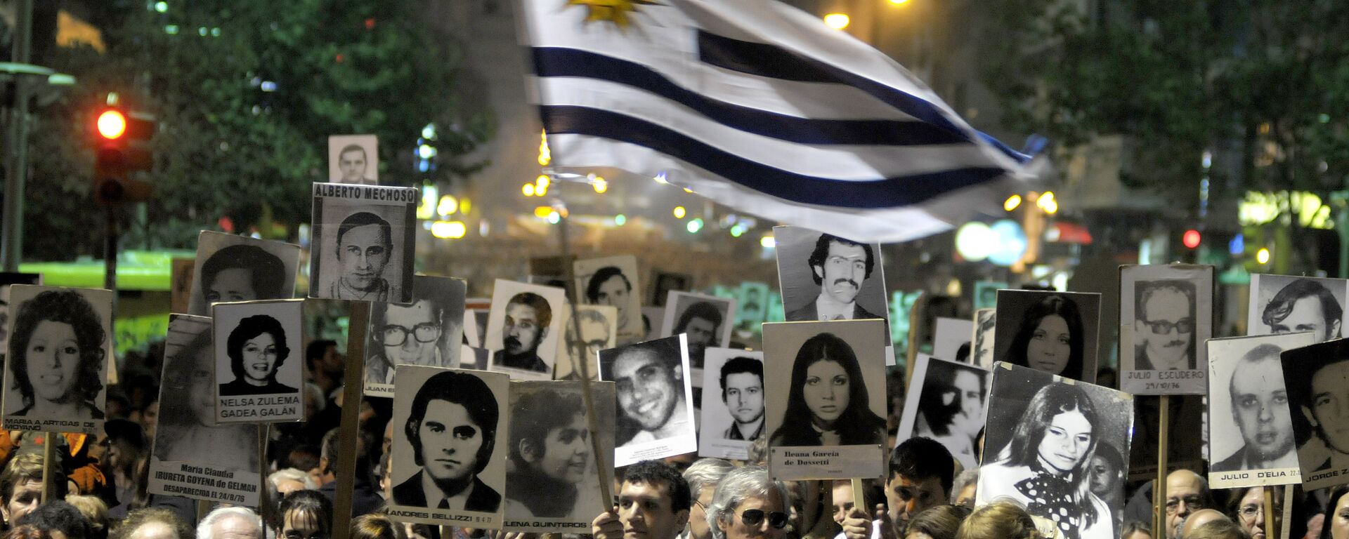 Demonstrators, one waving an Uruguayan flag, carry signs with images of people missing during Uruguay's 1973-85 dictatorship during a march in Montevideo, Uruguay - Sputnik Mundo, 1920, 04.05.2023