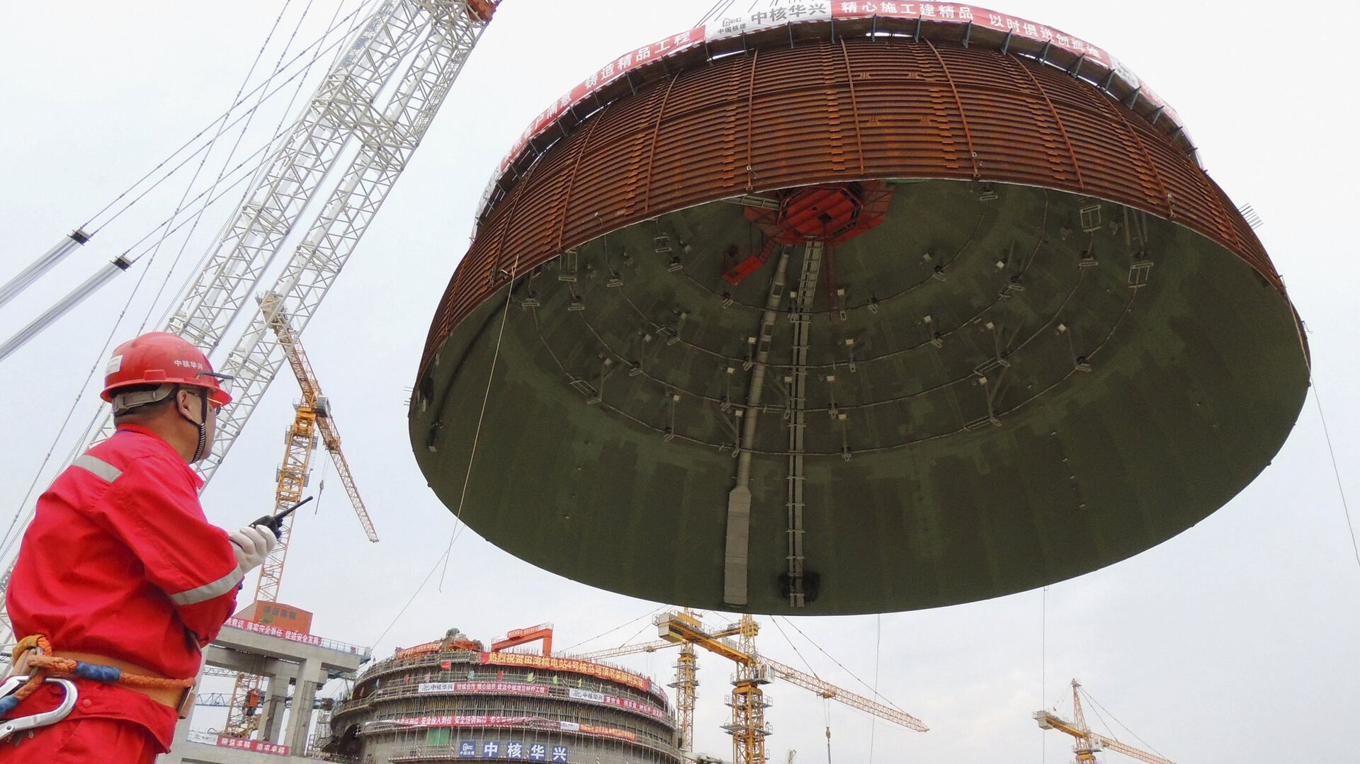 A worker looks on as the dome roof of a generator unit is lifted to be installed, at Tianwan Nuclear Power Plant, in Lianyungang, Jiangsu province, China, September 26, 2015. - Sputnik Mundo, 1920, 19.05.2021