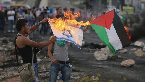A Palestinian protester burns a replica Israeli flag - Sputnik Mundo