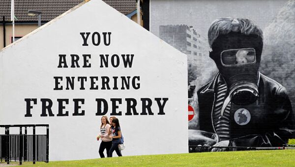 Niñas pasan junto a un mural 'Domingo Sangriento' en el área de Bogside de Londonderry, Irlanda del Norte - Sputnik Mundo
