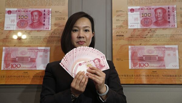 A staff member displays the new version of the 100-yuan RMB (US 15.7 dollars) banknotes for photographers at the Bank of China Tower in Hong Kong - Sputnik Mundo