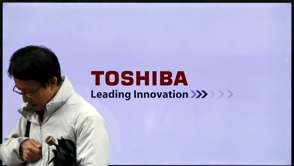 Un hombre pasa por un logo de la empresa japonesa Toshiba - Sputnik Mundo