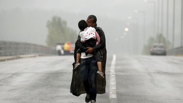 Refugiado sirio besa a su hija durante aguacero en la frontera entre Grecia y Macedonia - Sputnik Mundo
