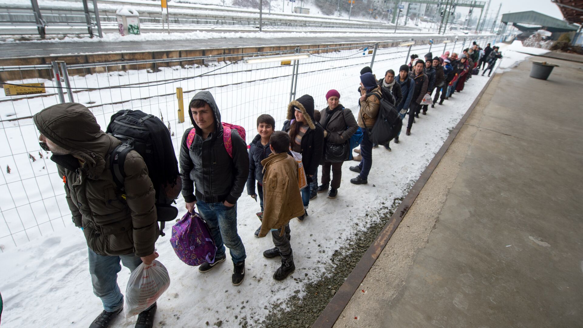 Refugees walk to a chartered train at the railway station of Passau, Germany Tuesday Jan. 5, 2016 - Sputnik Mundo, 1920, 07.12.2021
