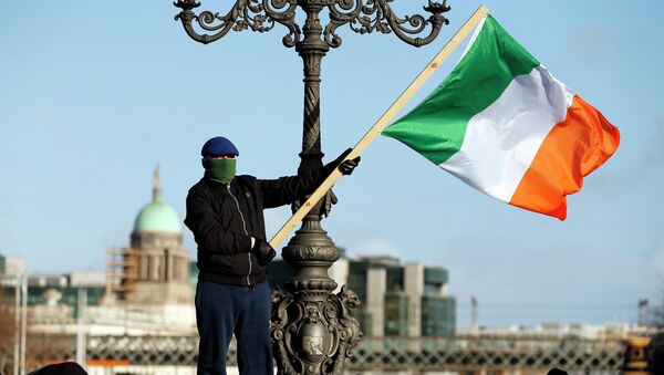 Un manifestante con la bandera de Irlanda - Sputnik Mundo
