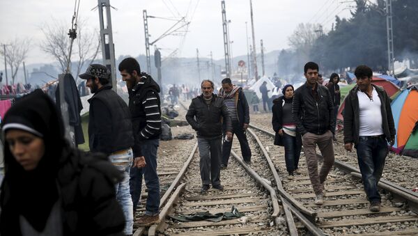 Refugees and migrants make their way along railway tracks at a makeshift camp at the Greek-Macedonian border near the village of Idomeni - Sputnik Mundo