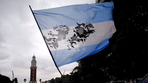 Un hombre agita una bandera argentina con una imagen de las Islas Malvinas - Sputnik Mundo