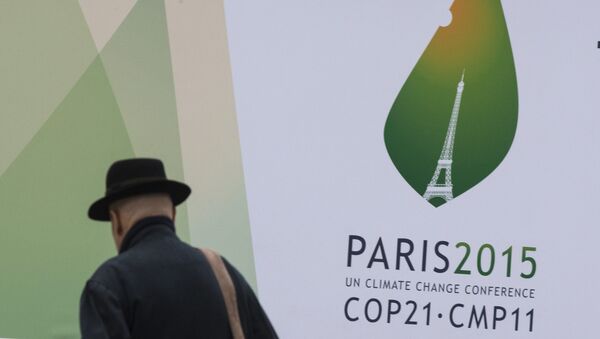 A passerby walks in front of posters for the forthcoming COP 21 World Climate Summit in Paris, France - Sputnik Mundo
