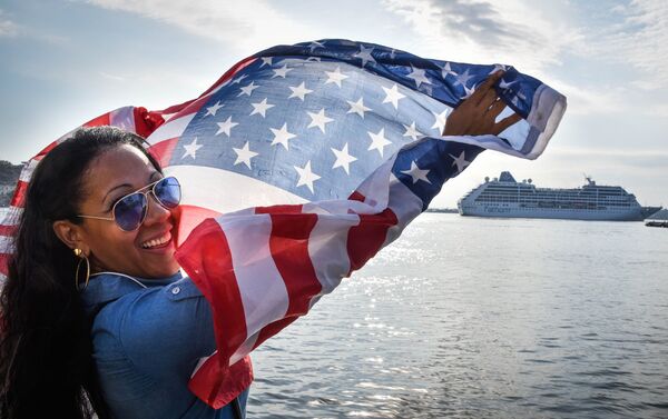 A Cuban waves a US flag at the Malecon waterfront as the first US-to-Cuba cruise ship to arrive in the island nation in decades glides into the port of Havana, on May 2, 2016. - Sputnik Mundo