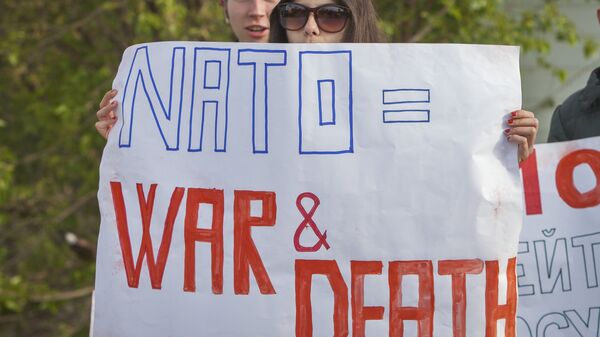 Activistas sosteniendo carteles anti-OTAN - Sputnik Mundo