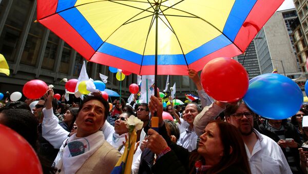 Colombianos celebrando con un paraguas con los colores de su bandera - Sputnik Mundo