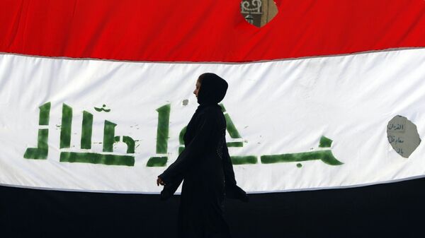 An Iraqi woman walks her national flag during a celebration marking the the departure of US troops from Iraq in Baghdad's Adhamiyah neighbourhood. File photo - Sputnik Mundo