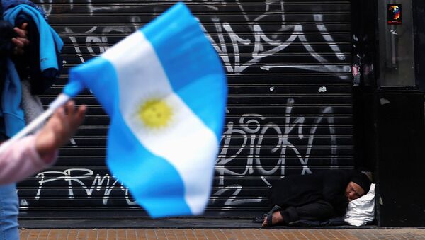 A woman sleeps on the sidewalk as a girl passes by holding an Argentine national flag during celebrations of the bicentennial anniversary of Argentina's independence from Spain in Buenos Aires - Sputnik Mundo