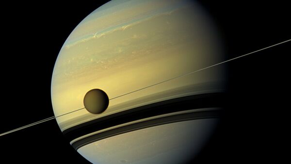 Saturn's largest moon Titan passing in front of the giant planet in an image made by NASA's Cassini spacecraft - Sputnik Mundo