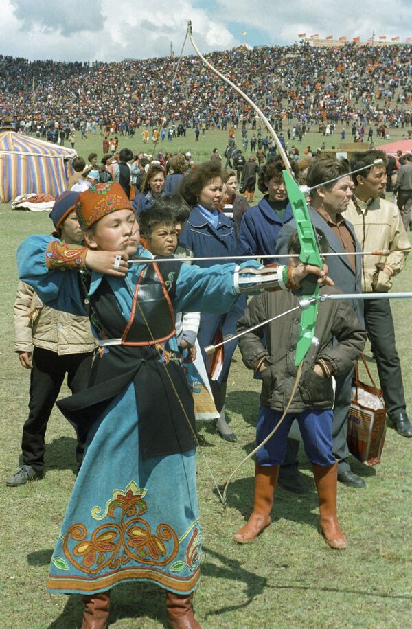 Joven de la república de Jakasia, ataviada con su traje nacional, dispara un arco. - Sputnik Mundo
