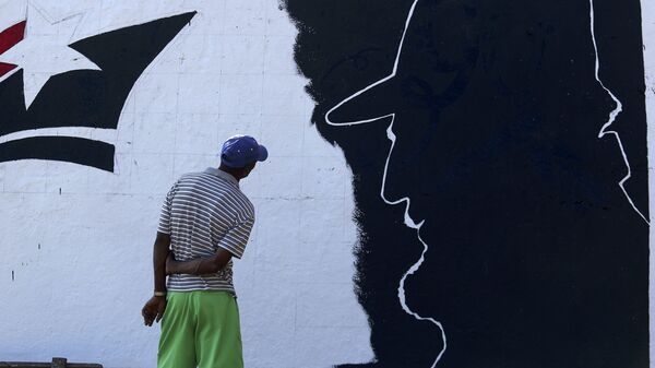 A man looks at a mural representing Cuba's late President Fidel Castro in the outskirts of Santiago de Cuba - Sputnik Mundo