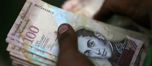A cashier counts Venezuelan bolivar notes at a street market in downtown Caracas A cashier counts Venezuelan bolivar notes at a street market in downtown Caracas - Sputnik Mundo