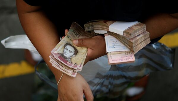 A customer counts Venezuelan bolivar notes at a market in downtown Caracas - Sputnik Mundo