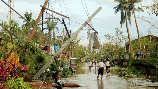 Residents walk past partially toppled electric posts after Typhoon Nock Ten hit Malinao, Albay in central Philippines December 26, 2016. - Sputnik Mundo