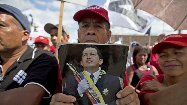 Un chavista en Venezuela con una fotografía de Hugo Chávez - Sputnik Mundo