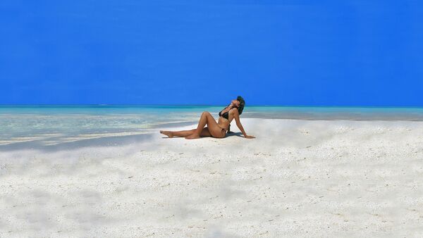 Una mujer toma sol en la playa - Sputnik Mundo