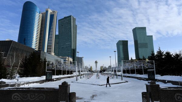 A picture taken on January 22, 2017 shows a man walking in downtown Astana, with the Baiterek monument seen in the background - Sputnik Mundo