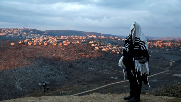 A Jewish man covered in a prayer shawl, prays in the Jewish settler outpost of Amona in the occupied West Bank December 18, 2016 - Sputnik Mundo