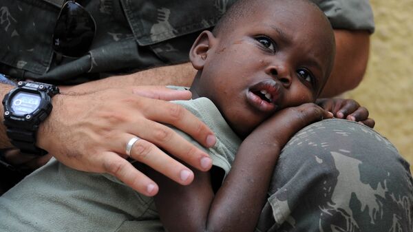Un niño de Haití, en el regazo de un Casco Azul - Sputnik Mundo