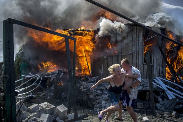 Lugareños de Stanitsa Lugánskaya huyen del incendio producido por un ataque de la Fuerza Aérea de Ucrania, 2 de julio de 2014 - Sputnik Mundo