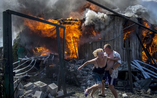 Lugareños de Stanitsa Lugánskaya huyen del incendio producido por un ataque de la Fuerza Aérea de Ucrania, 2 de julio de 2014. - Sputnik Mundo