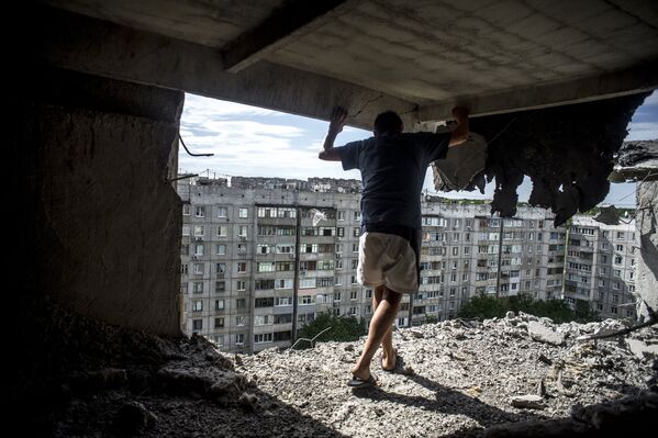 Un hombre examina los daños ocasionados por el bombardeo de la ciudad de Lugansk, 14 de julio de 2014 - Sputnik Mundo