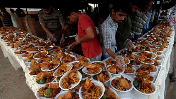 Unas personas organizan platos de comida para que los transeúntes interrumpan su ayuno durante un mes de Ramadán en Karachi - Sputnik Mundo