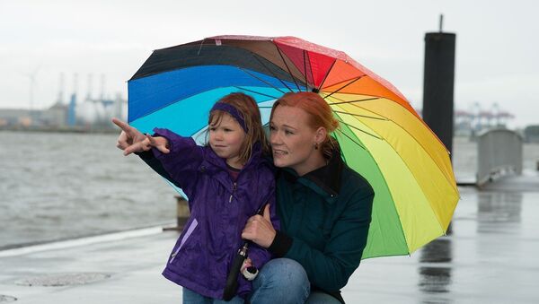 Una mujer con su hija bajo la lluvia - Sputnik Mundo