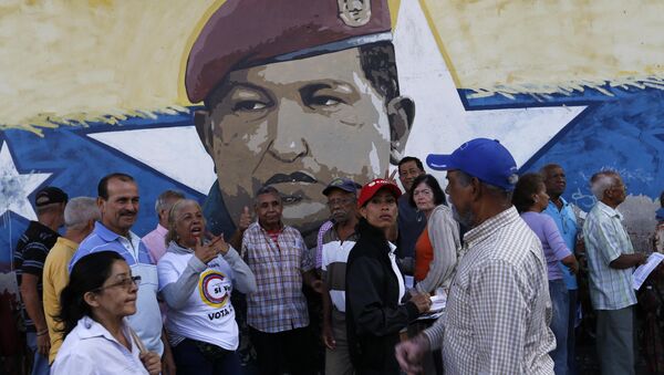 La gente venezolana ante una muralla con la imágen del expresidente de Venezuela, Hugo Chávez - Sputnik Mundo