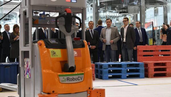 El fundador de RoboCV, Serguéi Máltsev (traje gris), presenta su robot-montacargas al primer ministro ruso, Dmitri Medvedev (a la izquierda de Máltsev) - Sputnik Mundo
