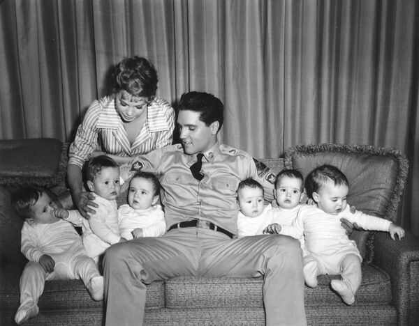 El cantante y actor Elvis Presley se presenta con seis bebés que aparecen en la película GI Blues y la co-estrella Juliet Prowse, izquierda, en Hollywood,  el 27 de junio de 1960. Los bebés son tres conjuntos de gemelos que se doblan entre sí en la película. - Sputnik Mundo