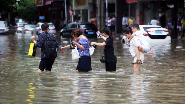 People walk through a flooded street as Typhoon Hato hits Dongguan, Guangdong province, China - Sputnik Mundo