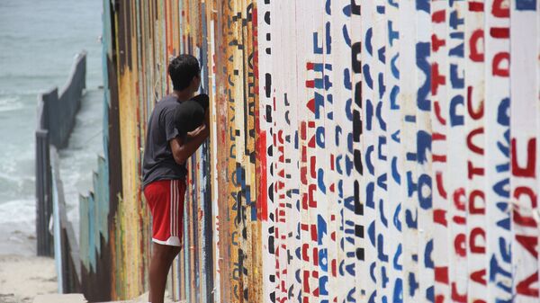 Un joven habla con sus familiares a través del muro que separa México y EEUU - Sputnik Mundo