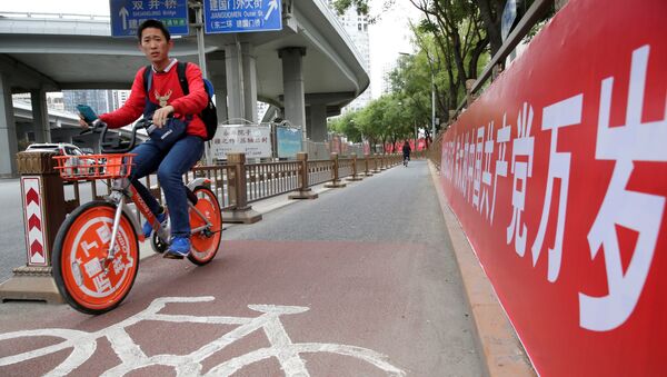 Un ciclista chino cerca del cartel que dice Que viva el gran partido Comunista de China - Sputnik Mundo