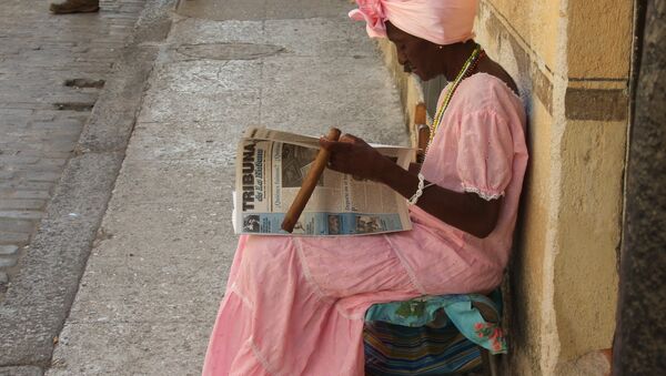 Una mujer cubana lee y fuma un puro en las calles de La Habana (imagen referencial) - Sputnik Mundo