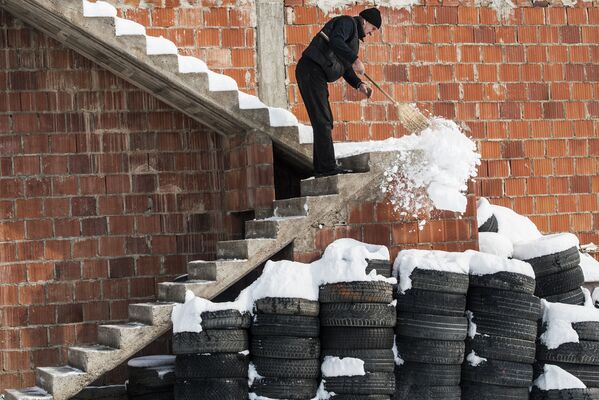 Un hombre quita la nieve de las escaleras de su casa después de una nevada en Kosovo. - Sputnik Mundo