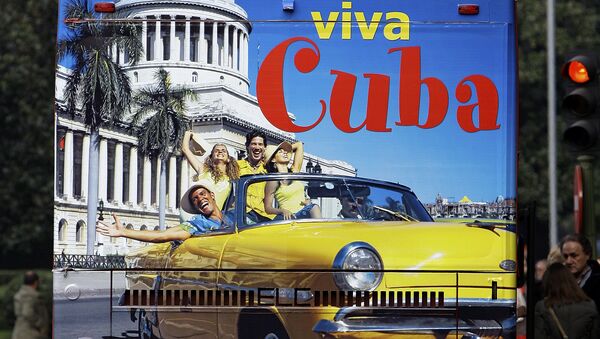 Un hombre en España sobre un bus de turismo que promociona el destino Cuba - Sputnik Mundo