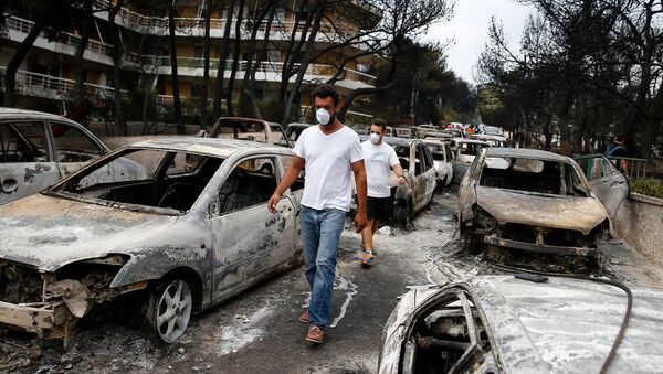 Dos hombres caminan entre autos calcinados después del incendio forestal en Grecia - Sputnik Mundo