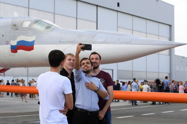 Los empleados de la planta se hacen una selfi con la aeronave de fondo durante la implementación de las pruebas terrestres y de vuelo del bombardero modernizado Tu-22M3M en la fábrica de aviones Gorbunov de Kazán - Sputnik Mundo