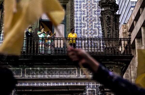 Trabajadores observan a los estudiantes que pasan con banderas de la UNAM durante la Marcha del Silencio 2018, en la Ciudad de México. Trabajadores observan a los estudiantes que pasan con banderas de la UNAM durante la Marcha del Silencio 2018, en la Ciudad de México. - Sputnik Mundo