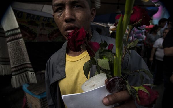 Hombre muestra los regalos recibidos por los demás fieles que reparten flores, dulces e imágenes Hombre muestra los regalos recibidos por los demás fieles que reparten flores, dulces e imágenes - Sputnik Mundo