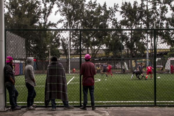 Integrantes del éxodo centroamericano miran un partido de fútbol entre Liverpool y Cuervos, en el deportivo de la Magdalena Mixhuca - Sputnik Mundo