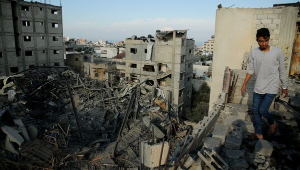 Un hombre camina en las ruinas de una edificación en Gaza - Sputnik Mundo